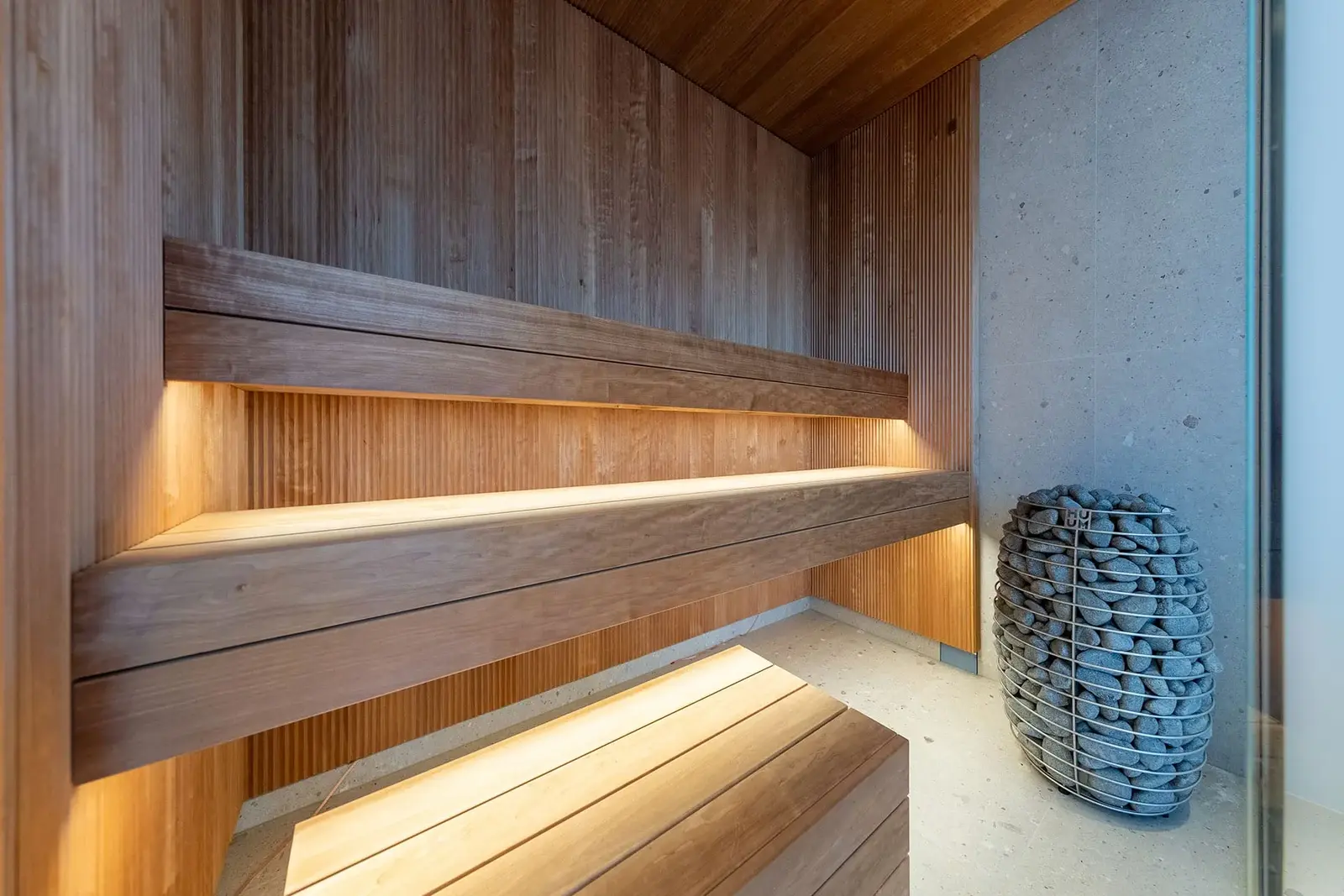 Thermory VIRE thermo-aspen wall panels with SHP thermo-aspen benches in a modern glass-front sauna
